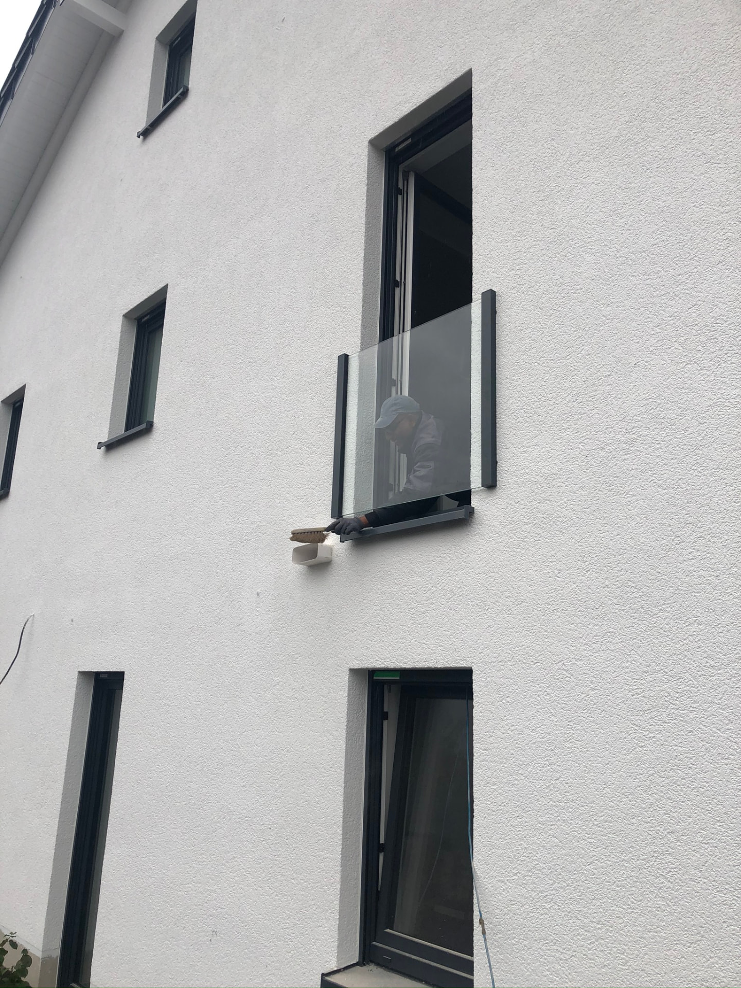 Französischer Balkon mit transparenter Glasfüllung als Absturzsicherung an einem weißen Haus