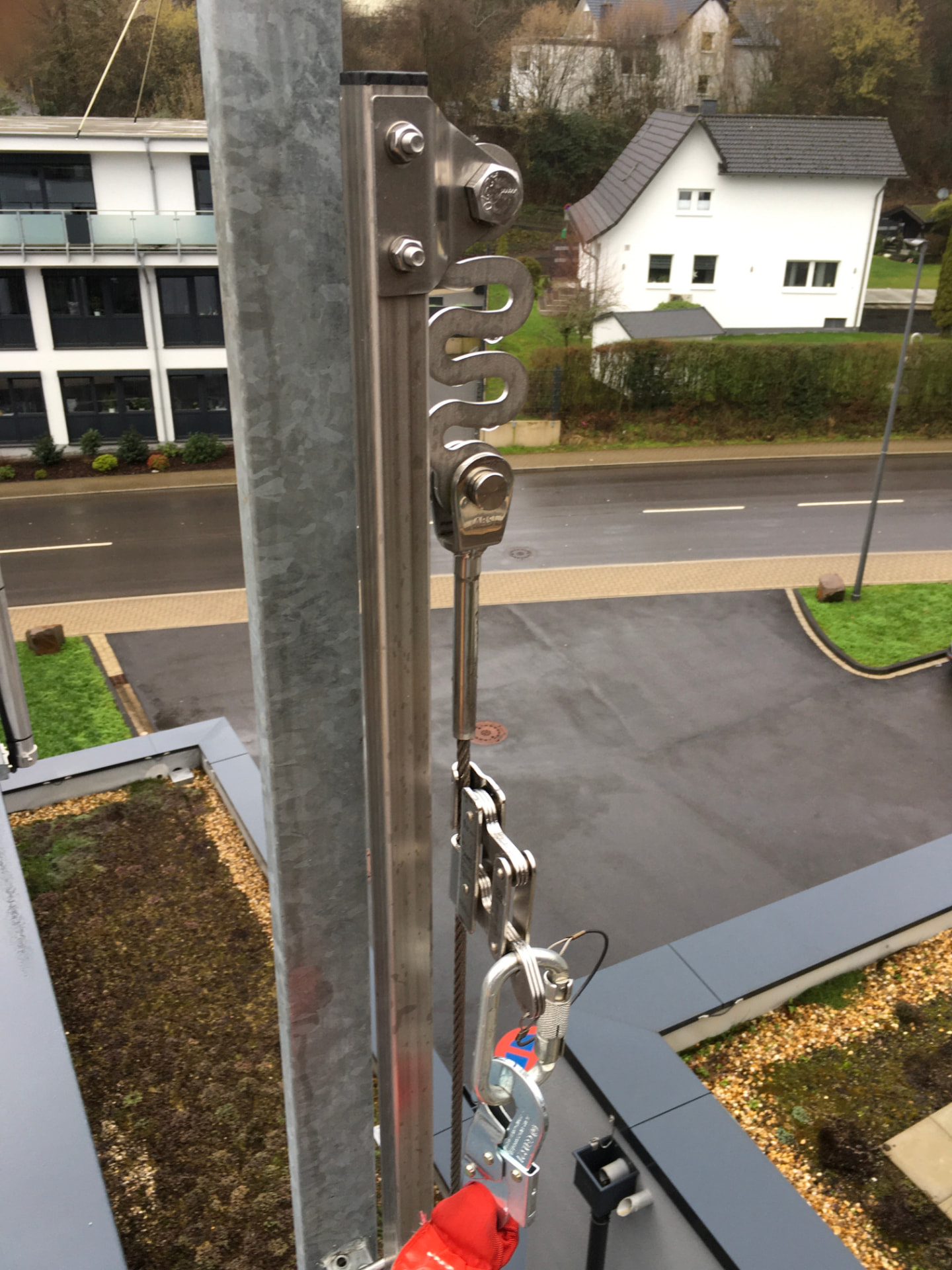 Detail einer Absturzsicherung aus Edelstahl mit Falldämpfer, Spanner und Karabiner an einer Dachkante