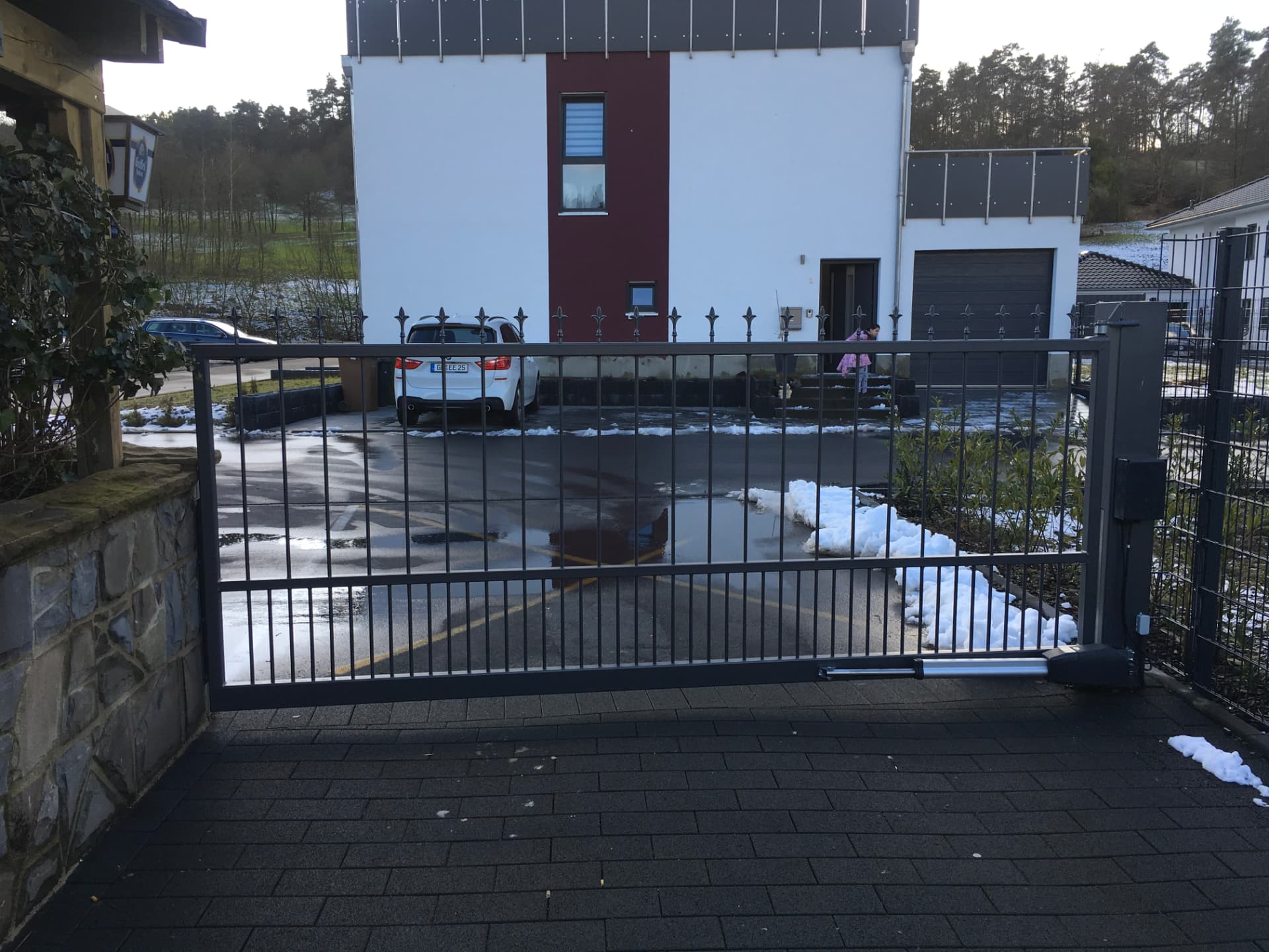 Elektrisch betriebenes Schiebetor aus Stahl an einer Grundstückseinfahrt