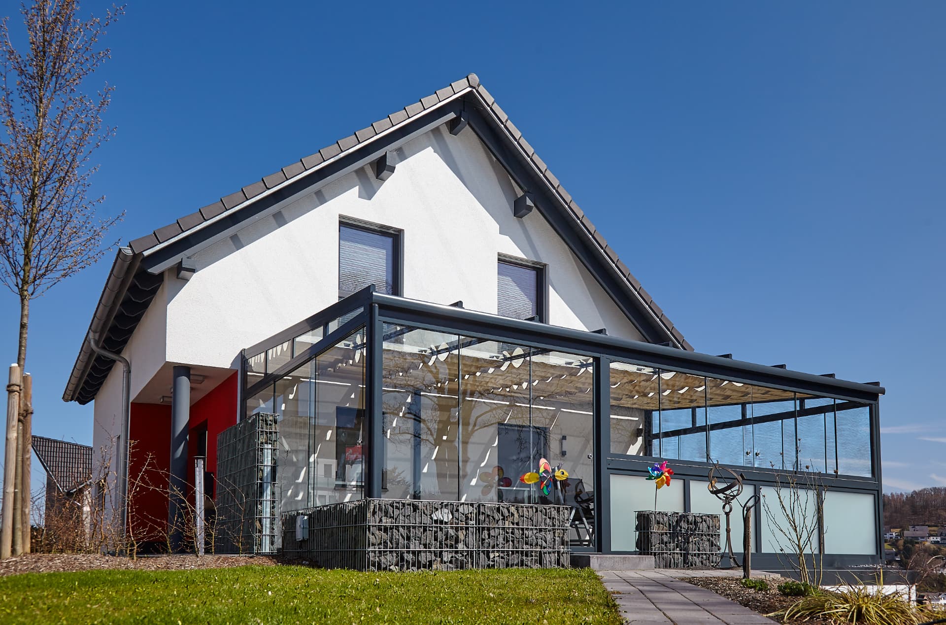 Große Terrassenüberdachung aus anthrazitfarbenem Stahlprofil und Glas an einem Einfamilienhaus